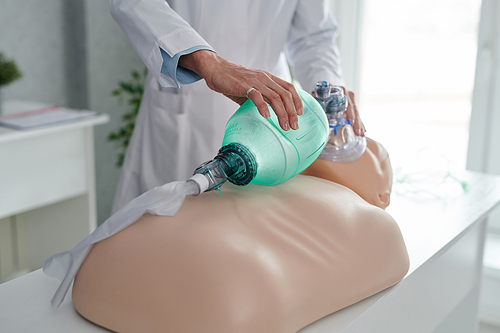 Close-up of medical specialist showing how to use oxygen mask on mannequin during lesson