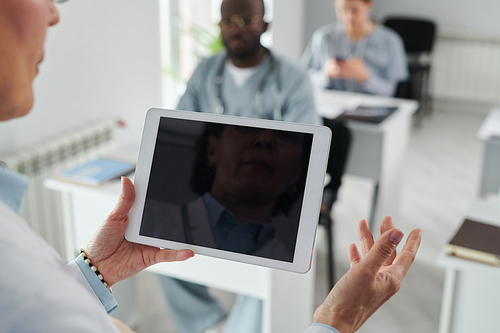 Close-up of female physician using digital tablet while speaking at conference for students