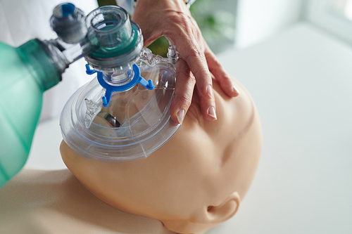 Close-up of nurse putting oxygen mask on face of mannequin and learning to use it during training