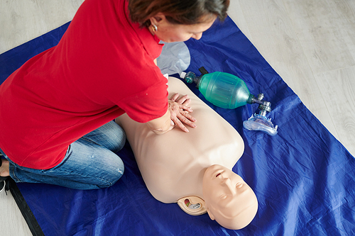 High angle view of paramedic doing heart massage on mannequin on floor