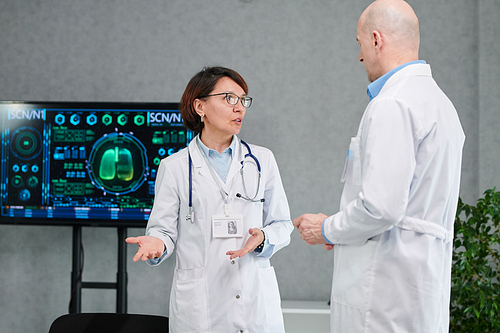 Two medical professionals in white coats discussing new medical technologies together after conference