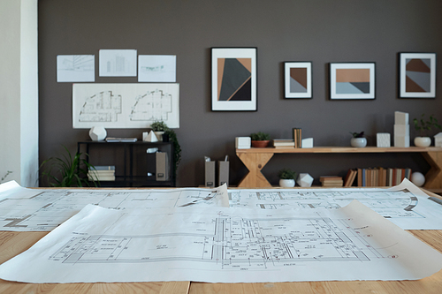 Interior of contemporary office of engineers or architects with large unrolled blueprint with sketch on their workplace
