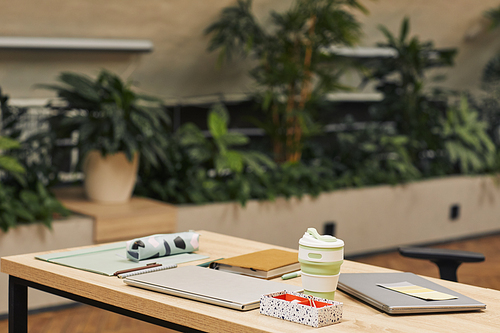 Background image of modern college library decorated with plants, focus on workplace with studying supplies in foreground, copy space