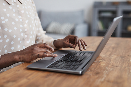 Close up of unrecognizable African-American woman using laptop at desk while working from home in apartment, copy space