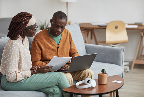 Portrait of contemporary African-American couple working together and holding documents in office interior, copy space