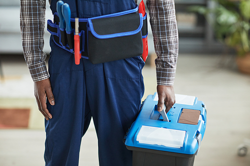 Cropped shot of unrecognizable African-American handyman holding toolbox while standing in home interior, copy space
