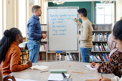 Group of modern immigrant students learning irregular verbs of English Language at school