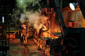 Group of workers working with metal in the factory