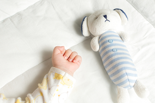 하얀이불위의 아기 손과 장난감 인형