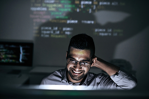 Smiling software developer looking on script on computer screen