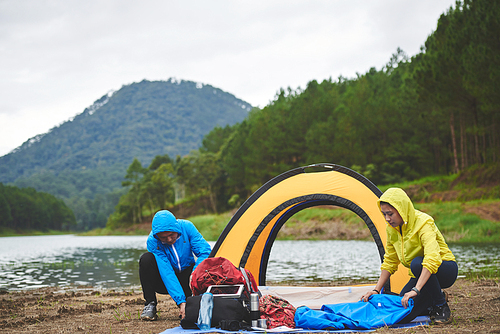 Asian couple setting up tent near the lake