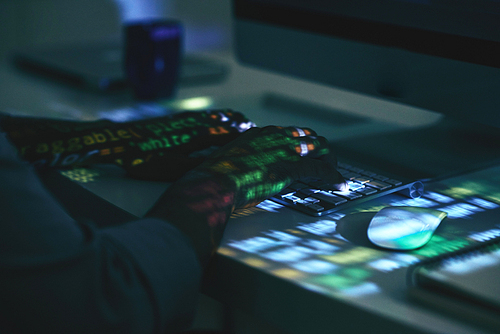 Hands of developer on keyboard in dark office