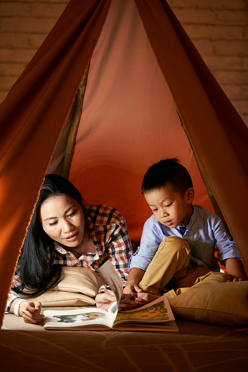 Little Asian boy and his mother reading together