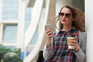 Portrait of pretty Vietnamese woman texting and drinking coffee