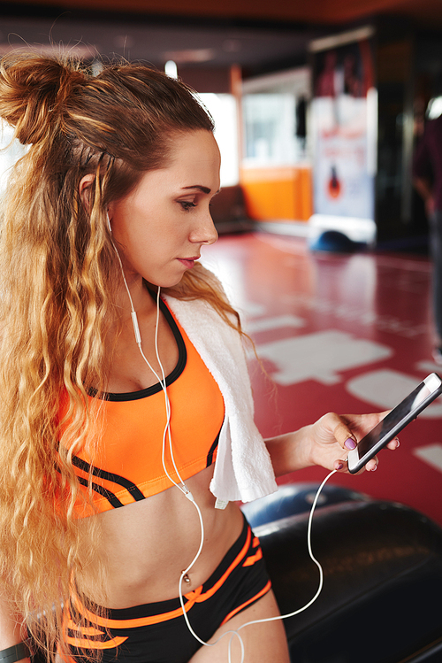 Pretty sportswoman searching for perfect music track for thraining