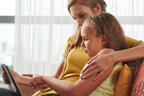 Mother hugging her daughter when they are watching tv shows