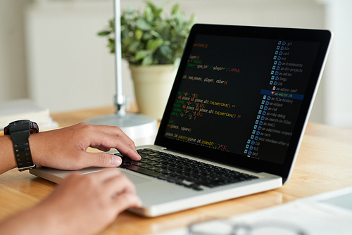 Hands of programmer writing code on laptop