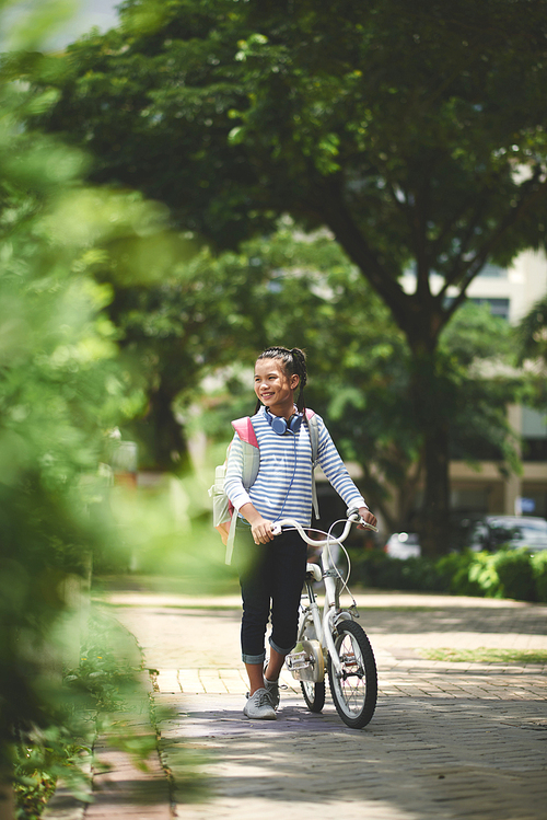 Full-length portrait of Asian girl with bicycle walking in the park