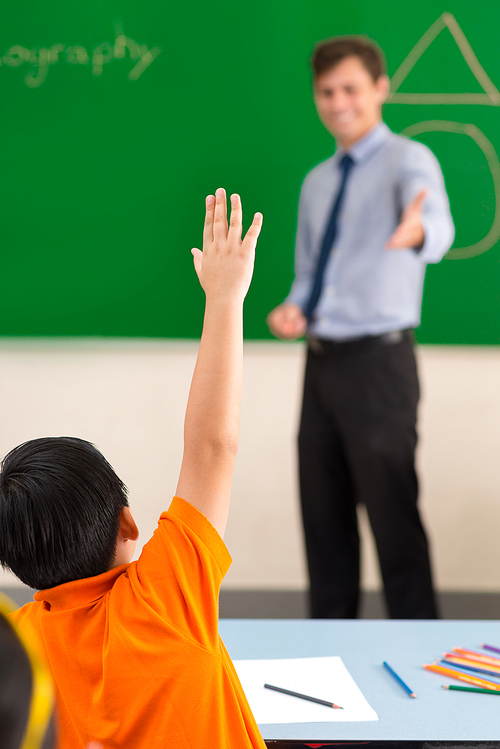 Schoolboy is willing to answer the question of the teacher