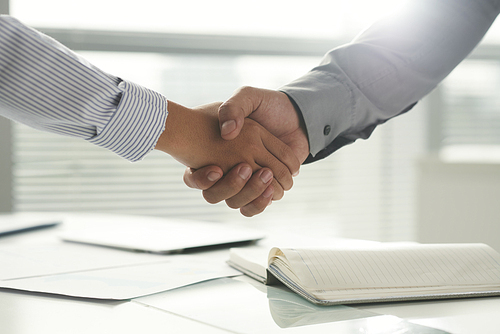 Close-up image of coworkers shaking hands after successful meeting