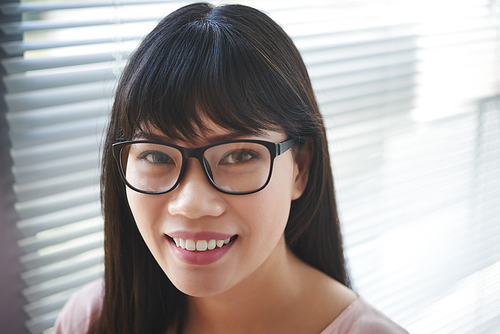 Face of Vietnamese smiling young woman in glasses