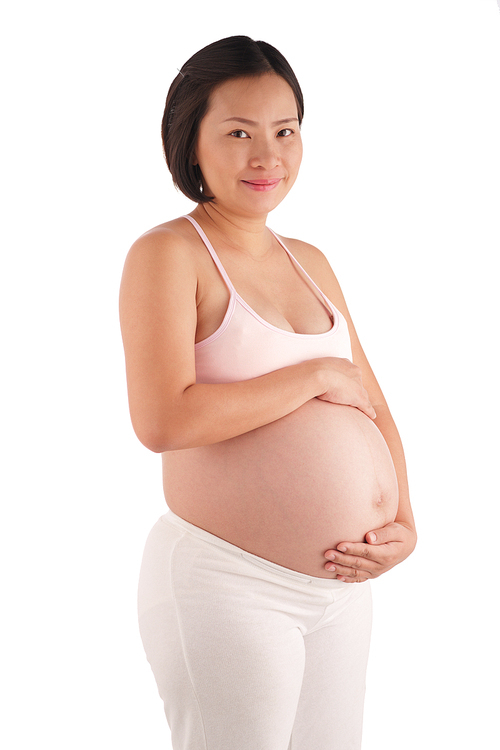 Attractive middle-aged pregnant woman caressing her belly while posing for photography against white background