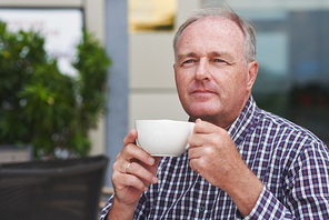 Portrait of mature man with cup of cappuccino