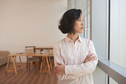 Pensive Japanese woman looking through office window