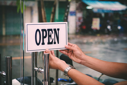 Hands of hairdresser turning card to open barbershop