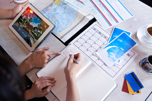 Close-up shot of unrecognizable couple taking necessary notes and planning vacation trip to Europe while sitting at table