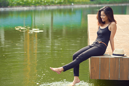 Beautiful young woman splashing water with legs