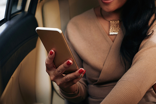 Smartphone in hand of woman who is sitting in taxi