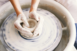 Hands of person working on pottery wheel
