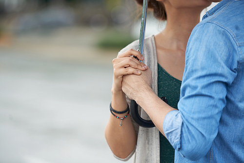 Closeup of young couple meet in rain, hold umbrella together and , copy space