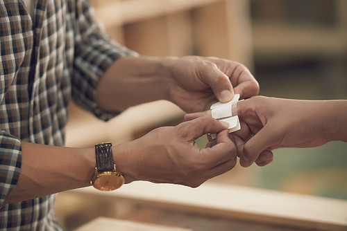 Hands of carpenter putting plaster on finger of his son