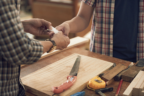 Man putting plaster on injured finger of son after working in joinery