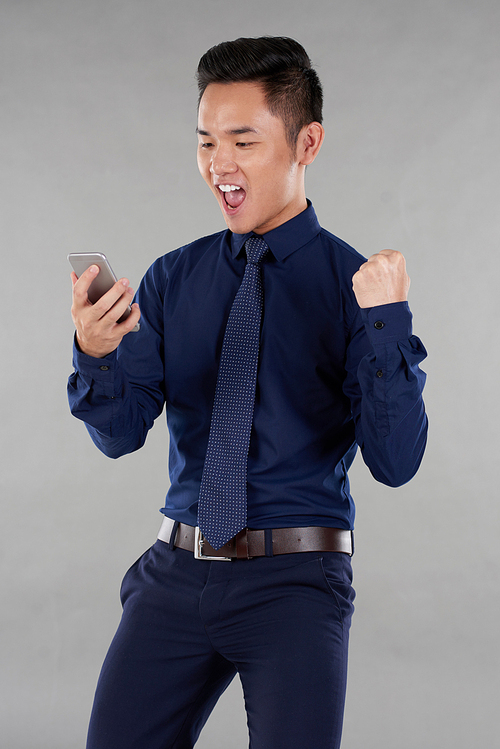 Excited happy young businessman reading good news on his smartphone