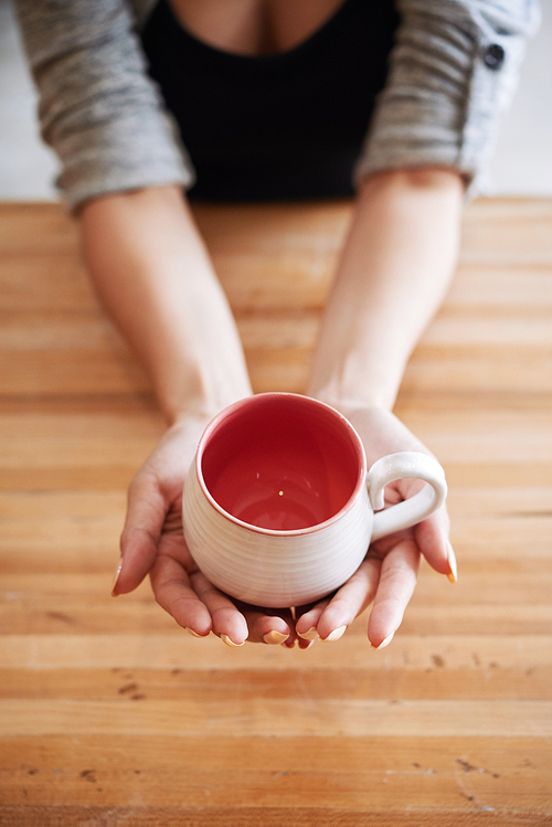 Finished mug in hands of female potter, view from above