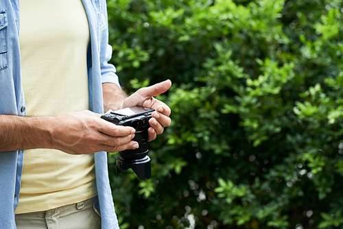 Close-up image of digital camera in hands of mature man