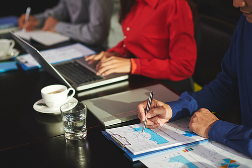 Hands of businessman examining financial report at meeting