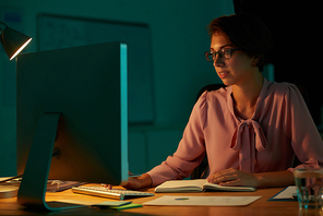 Business woman in glasses reading information on computer screen