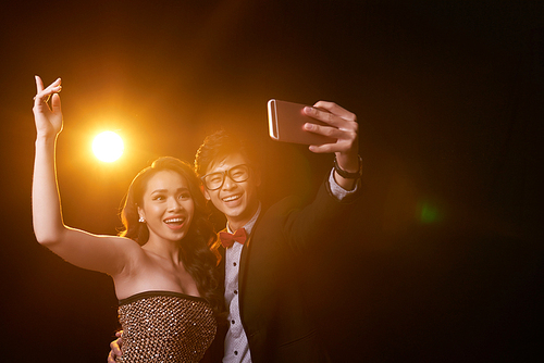 Laughing Vietnamese couple taking selfie at the party