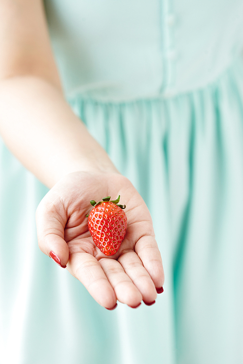 Hand of woman giving ripe strawberry to you
