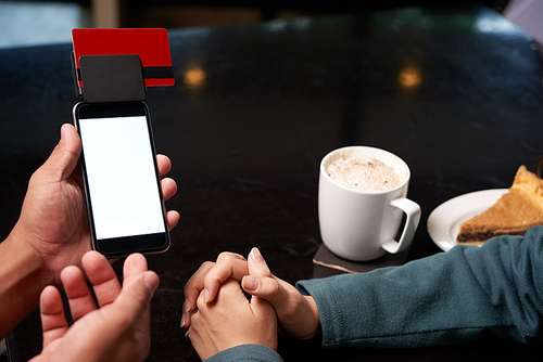 Waiter giving smartphone with card reader to customer so she can enter pin code