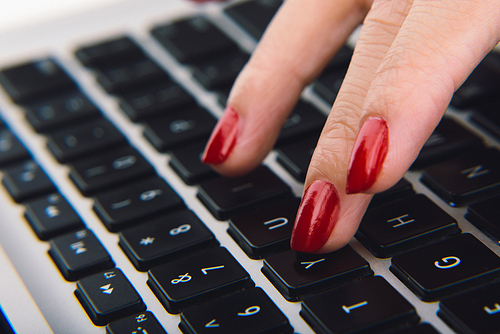 Close-up shot of young woman with ideal manicure typing on keyboard of modern laptop, close-up shot