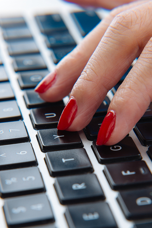Extreme close-up of female hand with ideal manicure lying on keyboard of modern laptop