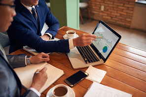 Businessman explaining chart on laptop screen to coworker