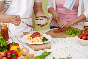 Man putting homemade bolognese sauce on spaghetti