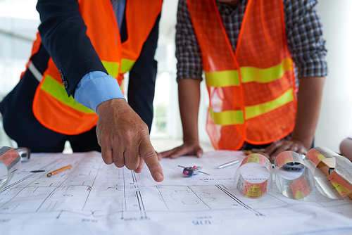 Close-up image of architect discussing blueprint with head engineer