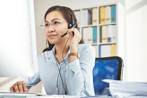 Cheerful Vietnamese business woman in headset working in office